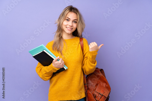 Teenager Russian student girl isolated on purple background pointing to the side to present a product