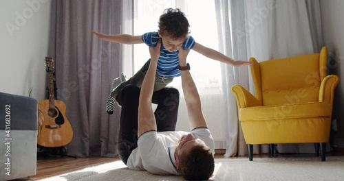 Sport time at home in the living room dad with his small cute son. 