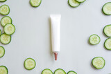 Moisturizer cream squeeze cosmetic tube with long nozzle and fresh sliced cucumber on green background with copy space. Natural organic cosmetics. Flatlay, mockup, top view.