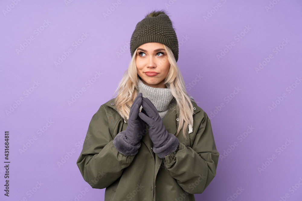 Teenager blonde girl with winter hat over isolated purple background scheming something Teenager blonde girl with winter hat over isolated purple background scheming something