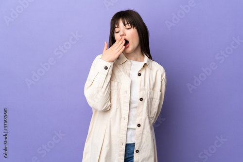 Young Ukrainian woman isolated on purple background yawning and covering wide open mouth with hand
