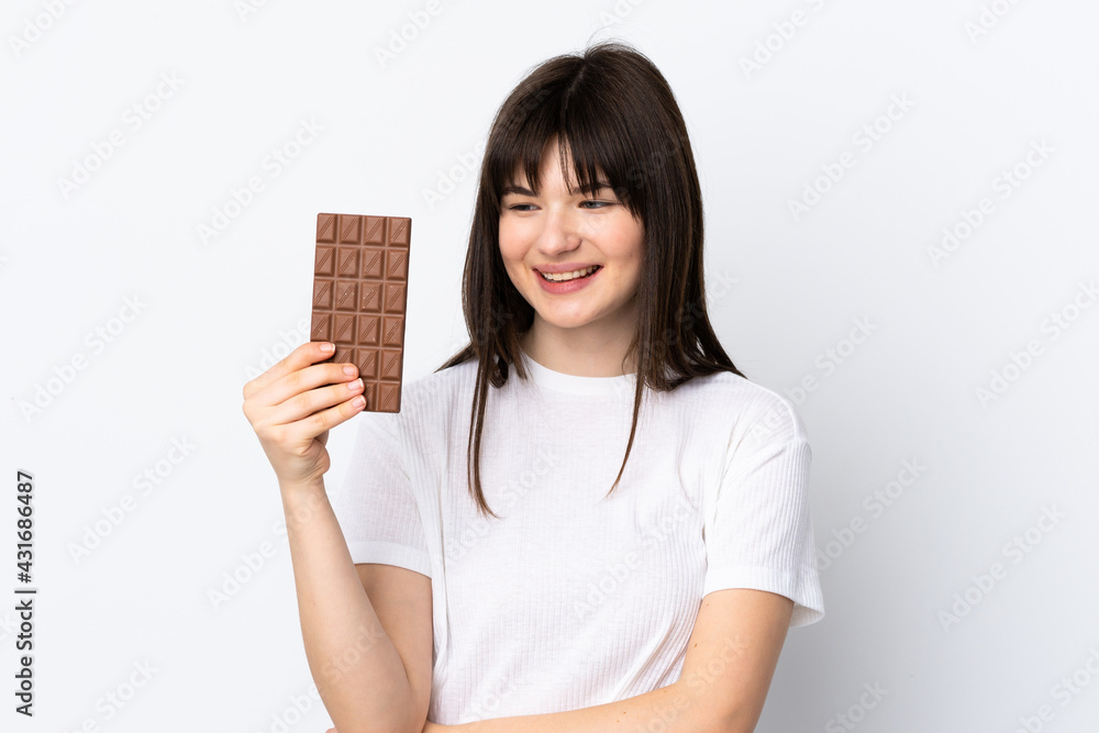 Young Ukrainian woman isolated on white background taking a chocolate tablet and happy Young Ukrainian woman isolated on white background taking a chocolate tablet and happy