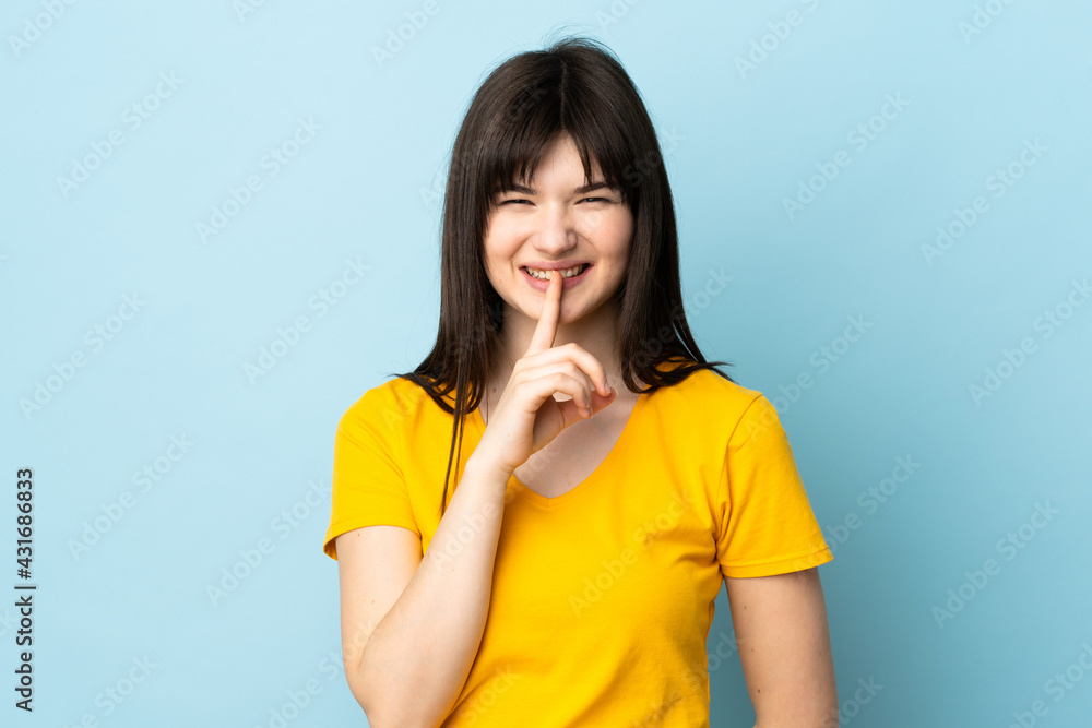 Teenager Ukrainian girl isolated on blue background showing a sign of silence gesture putting finger in mouth Teenager Ukrainian girl isolated on blue background showing a sign of silence gesture putting finger in mouth