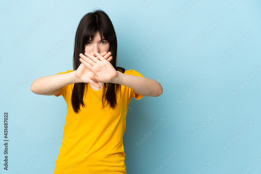 Teenager Ukrainian girl isolated on blue background making stop gesture with her hand to stop an act Teenager Ukrainian girl isolated on blue background making stop gesture with her hand to stop an act