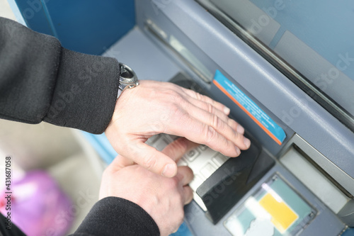 Man enters code on ATM keyboard and closes it with his hand