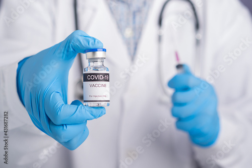 Doctor wearing a white uniform, medical gloves holding a syringe, and vaccine bottle for prepares vaccination. Vaccine for immunization, and treatment from coronavirus infection