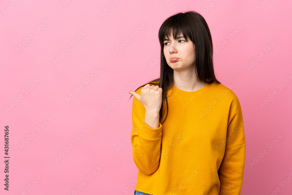 Young Ukrainian woman isolated on pink background unhappy and pointing to the side Young Ukrainian woman isolated on pink background unhappy and pointing to the side