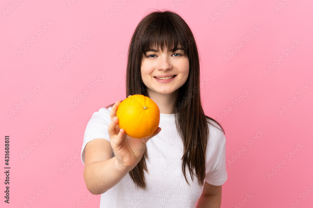 Young Ukrainian woman isolated on pink background holding an orange Young Ukrainian woman isolated on pink background holding an orange