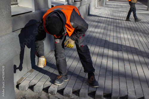 A worker levels the bricks with a hammer.