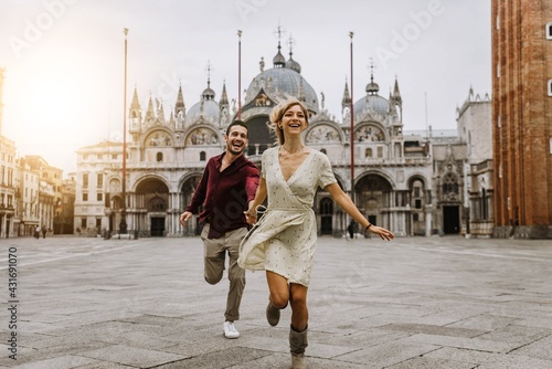 Couple of tourists visiting Venice, Italy - Boyfriend and girlfriend in love running together on city street at sunset - People, love and holidays concept © Davide Angelini
