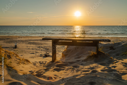 Empty wooden bench and beautiful golden sunset at the beach. Sun setting into the sea on tranquil evening. Nobody © CrispyMedia