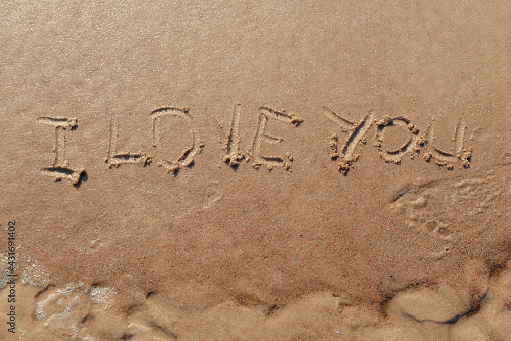 Fototapeta premium I love you sign whiten on the sand at the beach. Romantic love symbol at tropical seashore at sunset.