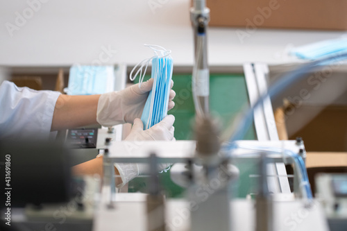 Close up of employees hands wearing gloves and packing medical face masks in a factory.