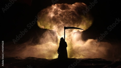 Nuclear war concept. Explosion of nuclear bomb. Creative artwork decoration in dark. Silhouette of grim reaper looking on giant mushroom cloud of atomic explosion. Selective focus photo