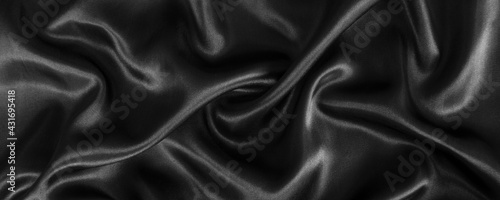 Abstract black silk fabric texture background. Cloth soft wave. Creases of satin