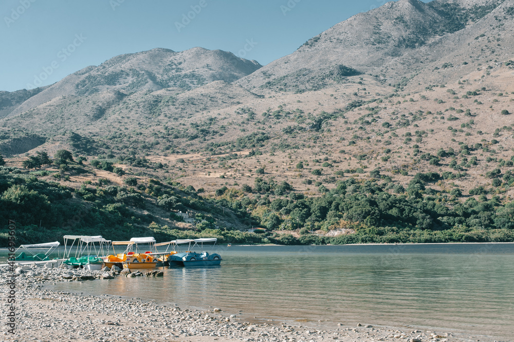Catamarans on the coast of lake Kournas wtih mountains in background