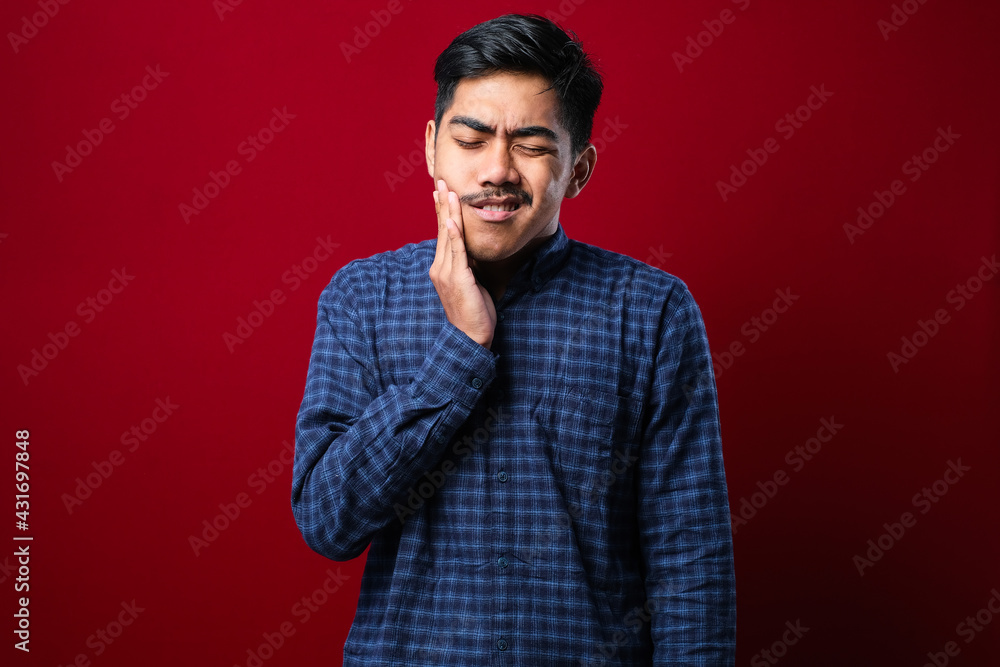 Obraz premium Young handsome man wearing casual shirt standing over isolated red background touching mouth with hand with painful expression