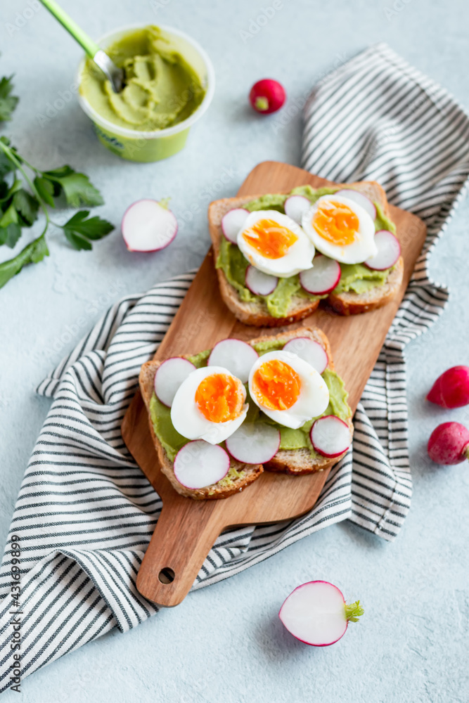 Healthy avocado and egg toasts for breakfast on board, top view, natural lighting Healthy avocado and egg toasts for breakfast on board, top view, natural lighting