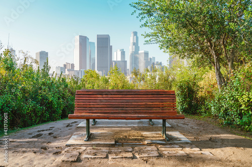An empty bench in a Los Angeles park with a view of Downtown skyscrapers. Morning in summer. Los Angeles, USA - 16 Apr 2021
