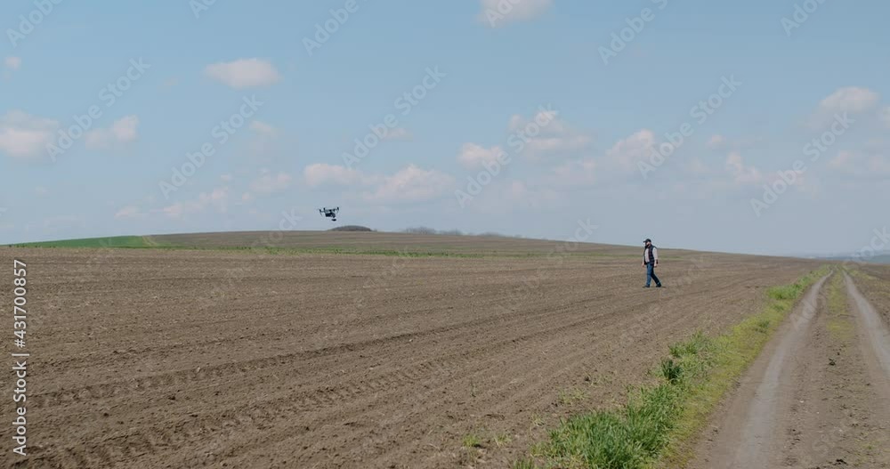 A farmer walks in the field and uses a modern drone. technology. A farmer walks in the field and uses a modern drone. technology.