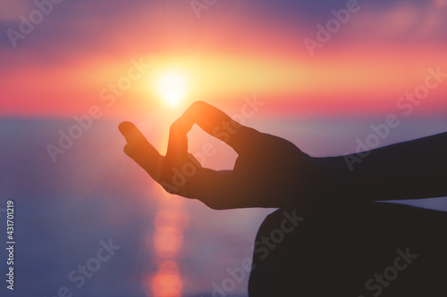 Young woman practicing yoga at sunset or morning sea beach, spiritual practice, mental health and mind relaxation