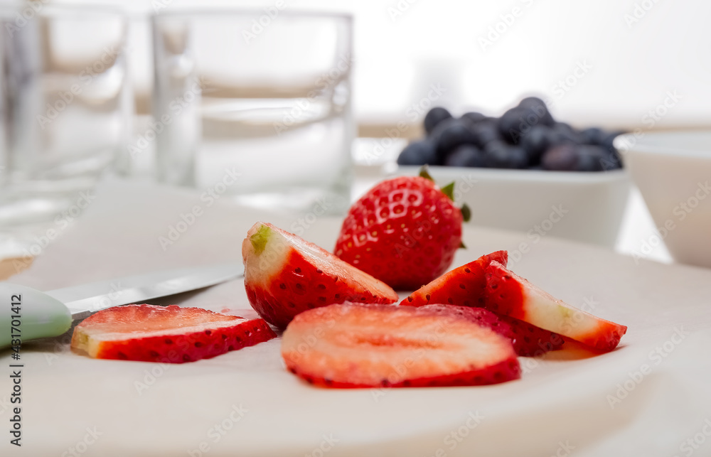 Chef's knife and slices of strawberries on a cutting board. Baking paper. Healthy food concept. High quality photo Chef's knife and slices of strawberries on a cutting board. Baking paper. Healthy food concept. High quality photo