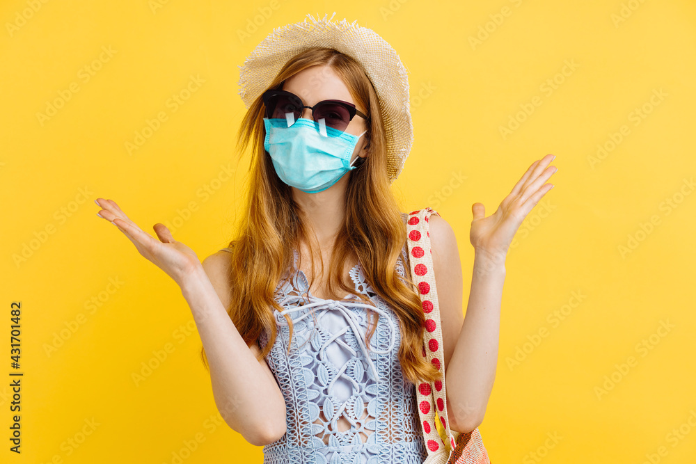 Young happy woman in medical protective mask and summer hat, in summer clothes, on yellow background Young happy woman in medical protective mask and summer hat, in summer clothes, on yellow background