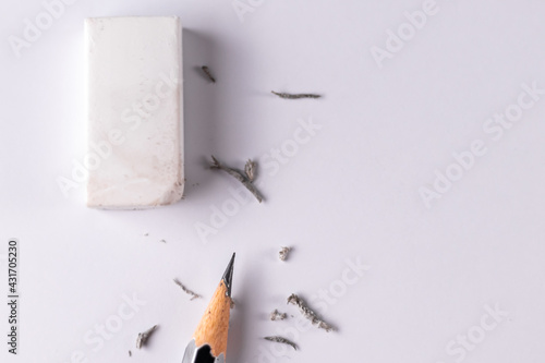 Top close up shot of an eraser with a pencil and waste left after erasing on white paper - Education concept.