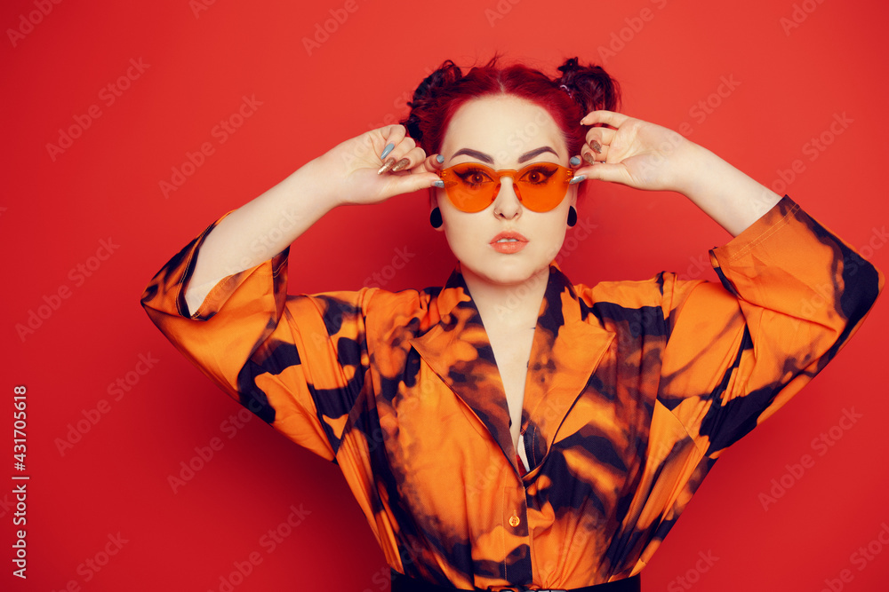 Cute girl on a red background. Red hair and tunnels in the ears, red dress  and