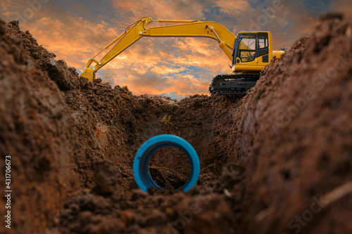 Crawler excavator is digging in the construction site pipeline work on sunset sky background photo