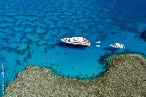Aerial view: Luxury Yacht and small boat, parking to coral reef in the Red Sea, Egypt © Антон Яковлев