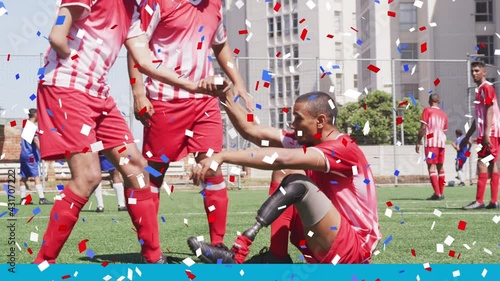 Colorful confetti falling against disabled male soccer player helping his teammate to get up