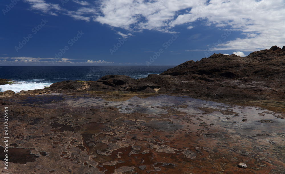 Gran Canaria, calm natural seawater pools in under the steep cliffs of the north coast, separated from the ocean by 
volcanic rock, Punta de Galdar area
