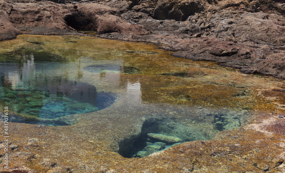 Gran Canaria, calm natural seawater pools in under the steep cliffs of the north coast, separated from the ocean by 
volcanic rock, Punta de Galdar area