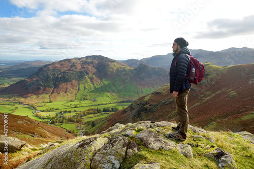 Male tourist enjoying sunset view of Great Langdale valley in the Lake District, famous for its glacial ribbon lakes and rugged mountains.