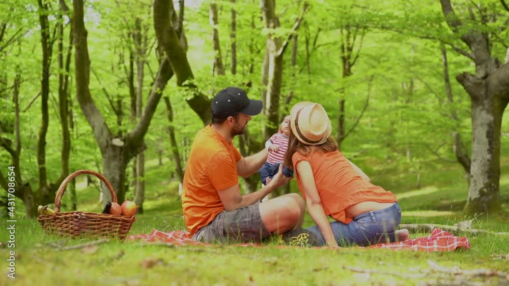 A family on a picnic day with their newborn son. Dressed in orange t-shirts and hats, summer vacation lifestyle A family on a picnic day with their newborn son. Dressed in orange t-shirts and hats, summer vacation lifestyle