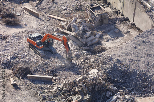 An aerial view taken from a helicopter of a power station during demolition. An excavator is breaking up reinforced concrete using a jack hammer.