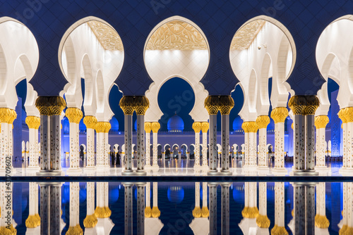 Sheikh Zayed Grand Mosque arches reflected in pool at night.