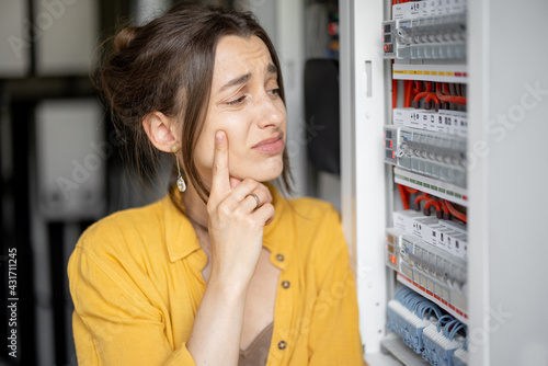 Confused woman having problems with electricity at home, speaks on the phone trying to solve the problem. Concept of female incompetence in home electricity photo