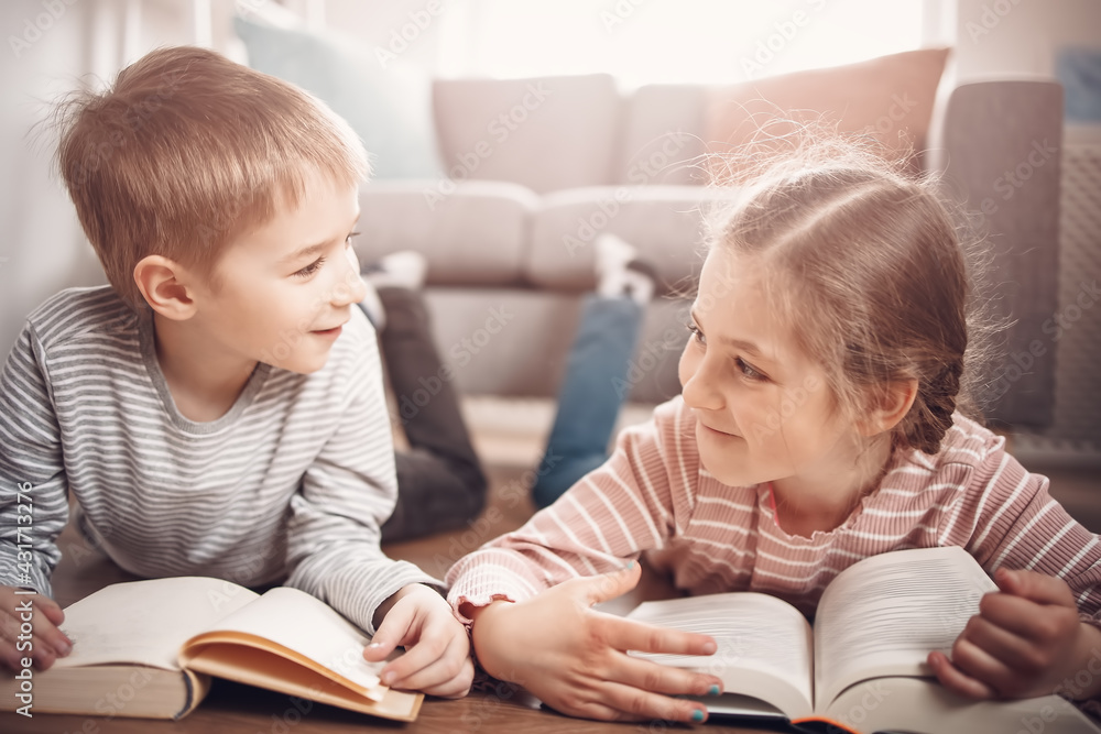 Cute children lying down on the floor and reading books Cute children lying down on the floor and reading books