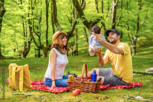 A family on a picnic day with their newborn son. Dressed in a white and yellow t-shirt
