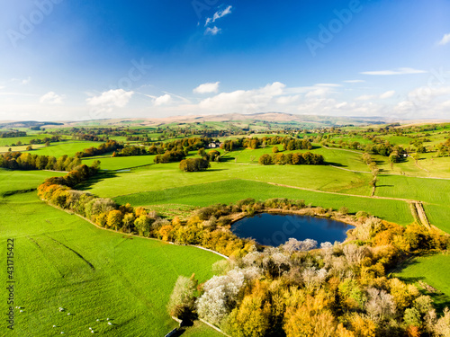 Fototapeta Naklejka Na Ścianę i Meble -  Aerial view of endless lush pastures and farmlands of England. Beautiful English countryside with emerald green fields and meadows.