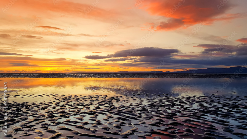 Beautiful sunset colors over the coastline of Allerdale district in Cumbria, UK. Sun setting over the shore of Allonby bay on autumn.