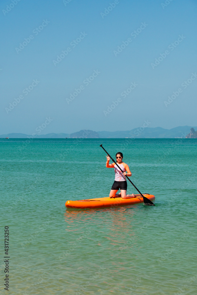 young sporty woman playing stand-up paddle board on the blue sea in sunny day of summer vacation