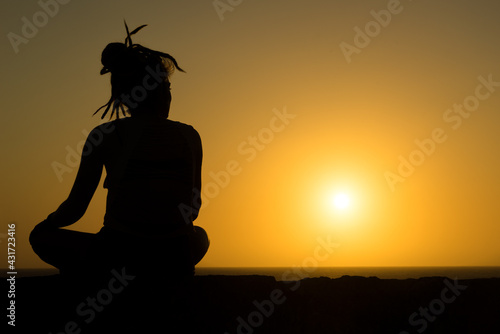 A young woman watches the sunset from atop a wall in Cartagena, Colombia.