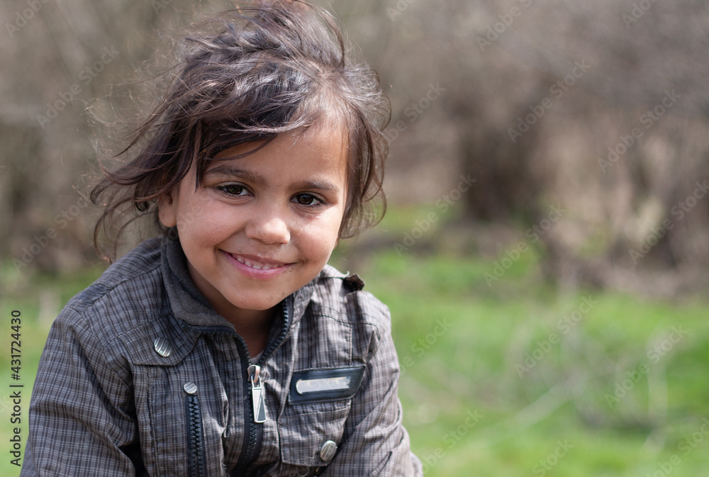 A portrait of smiling beautiful little gypsy girl in a Roma settlement A portrait of smiling beautiful little gypsy girl in a Roma settlement