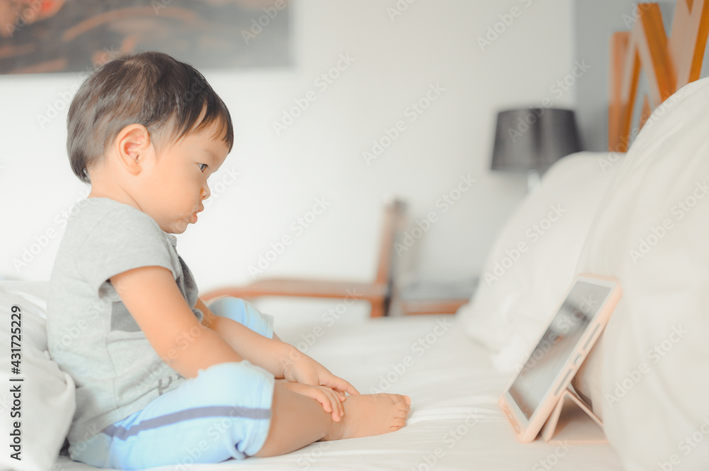 Little asian boy lying in bed and watch a story on touchscreen tablet,Early age education development. Video chat, video call. Little asian boy lying in bed and watch a story on touchscreen tablet,Early age education development. Video chat, video call.