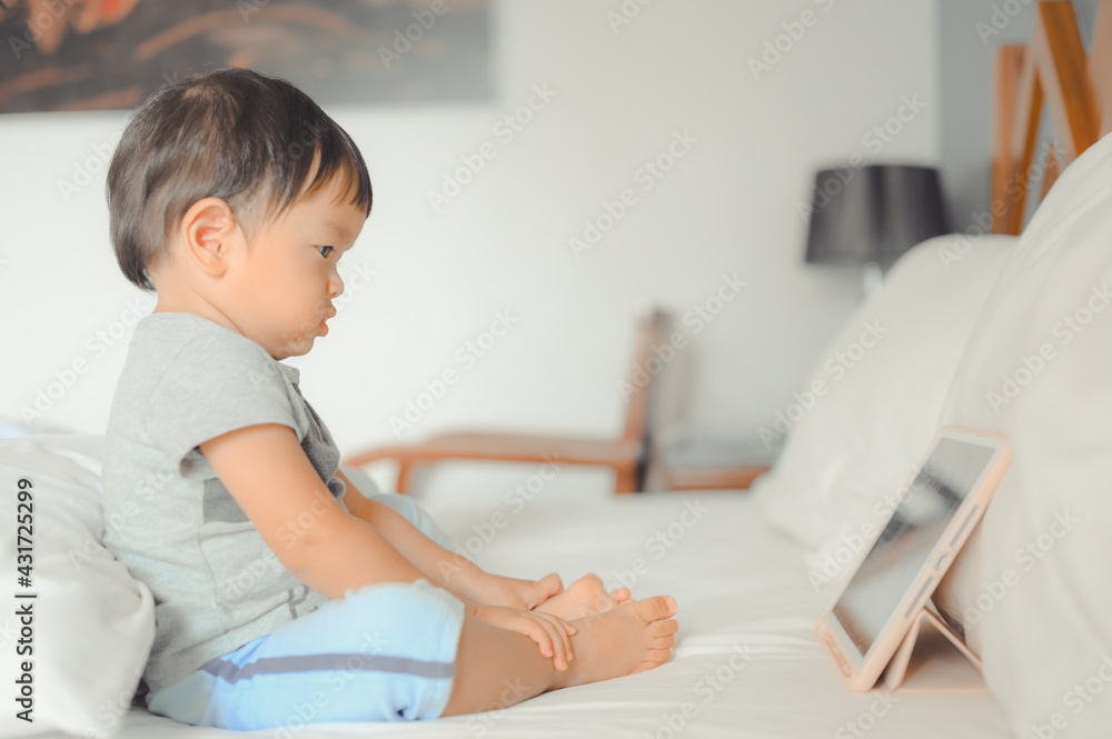 Little asian boy lying in bed and watch a story on touchscreen tablet,Early age education development. Video chat, video call. Little asian boy lying in bed and watch a story on touchscreen tablet,Early age education development. Video chat, video call.