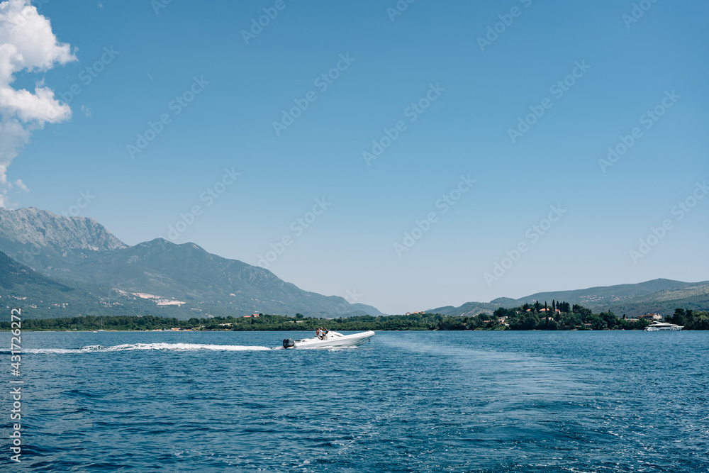 Tourists ride on white. sports boat in the sea against the backdrop of mountains in Montenegro. The concept of rich life and travel around the world.