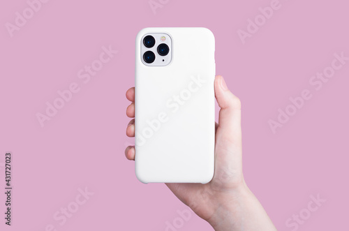 Female hand holding white iPhone 11 Pro in soft silicone white cover back view . Phone case mock up isolated on pink background , iPhone 12